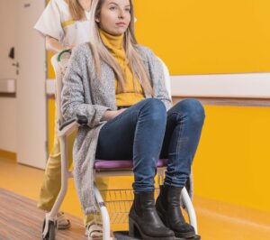 ošetřovatelka v rezidenčním zařízení veze ženu na vozíku